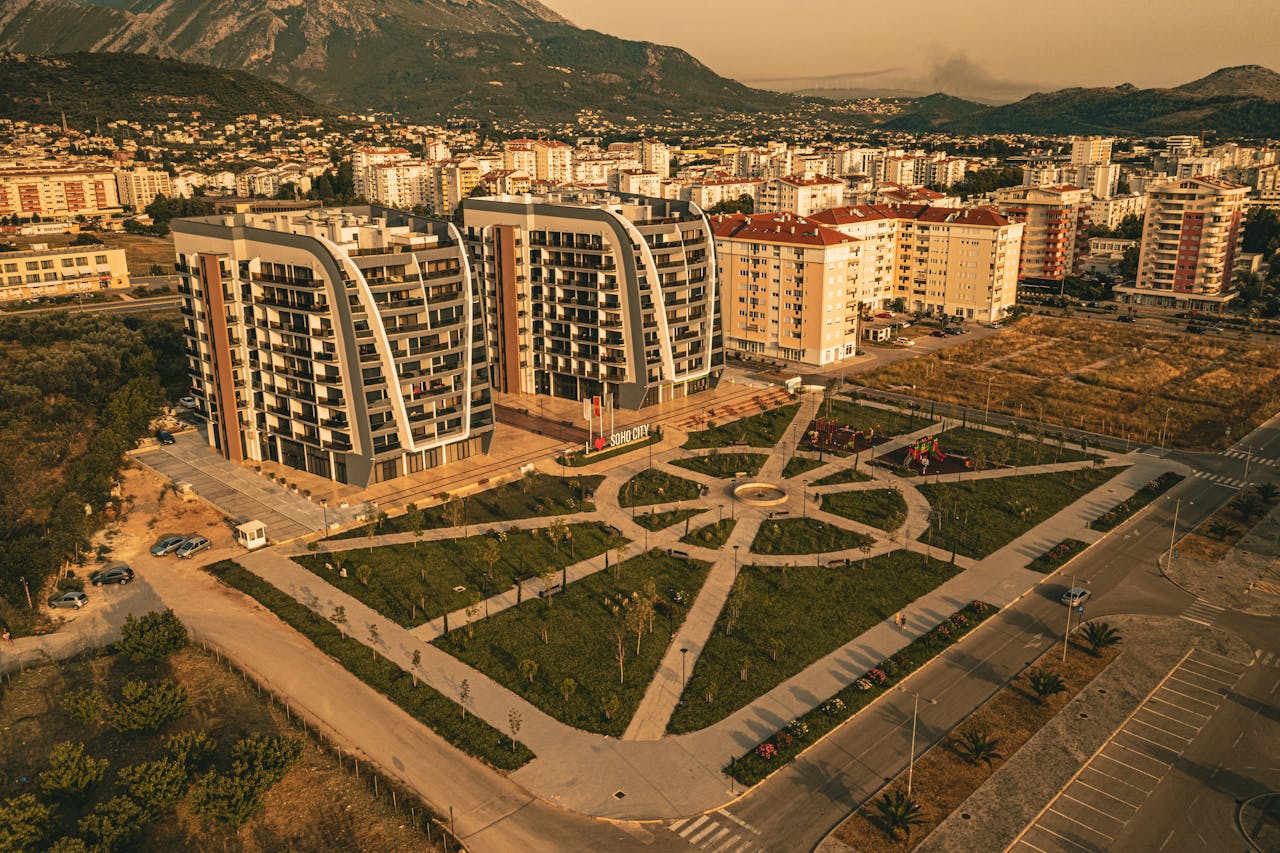 Aerial view of a modern apartment complex surrounded by urban landscape and mountains.