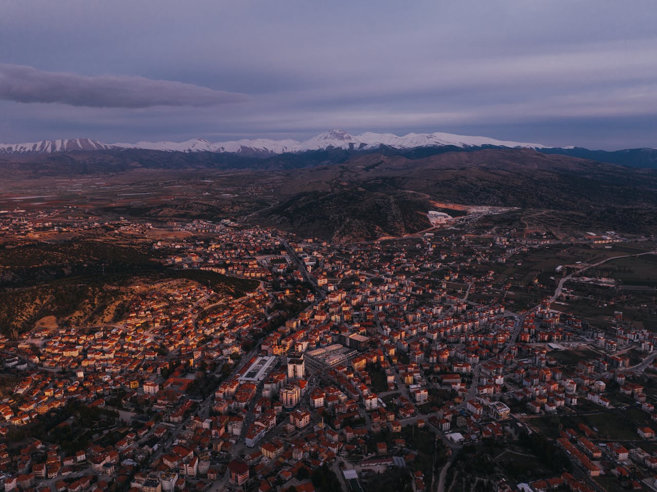 Captivating aerial view of a city in Turkey at sunset with stunning mountain backdrop.